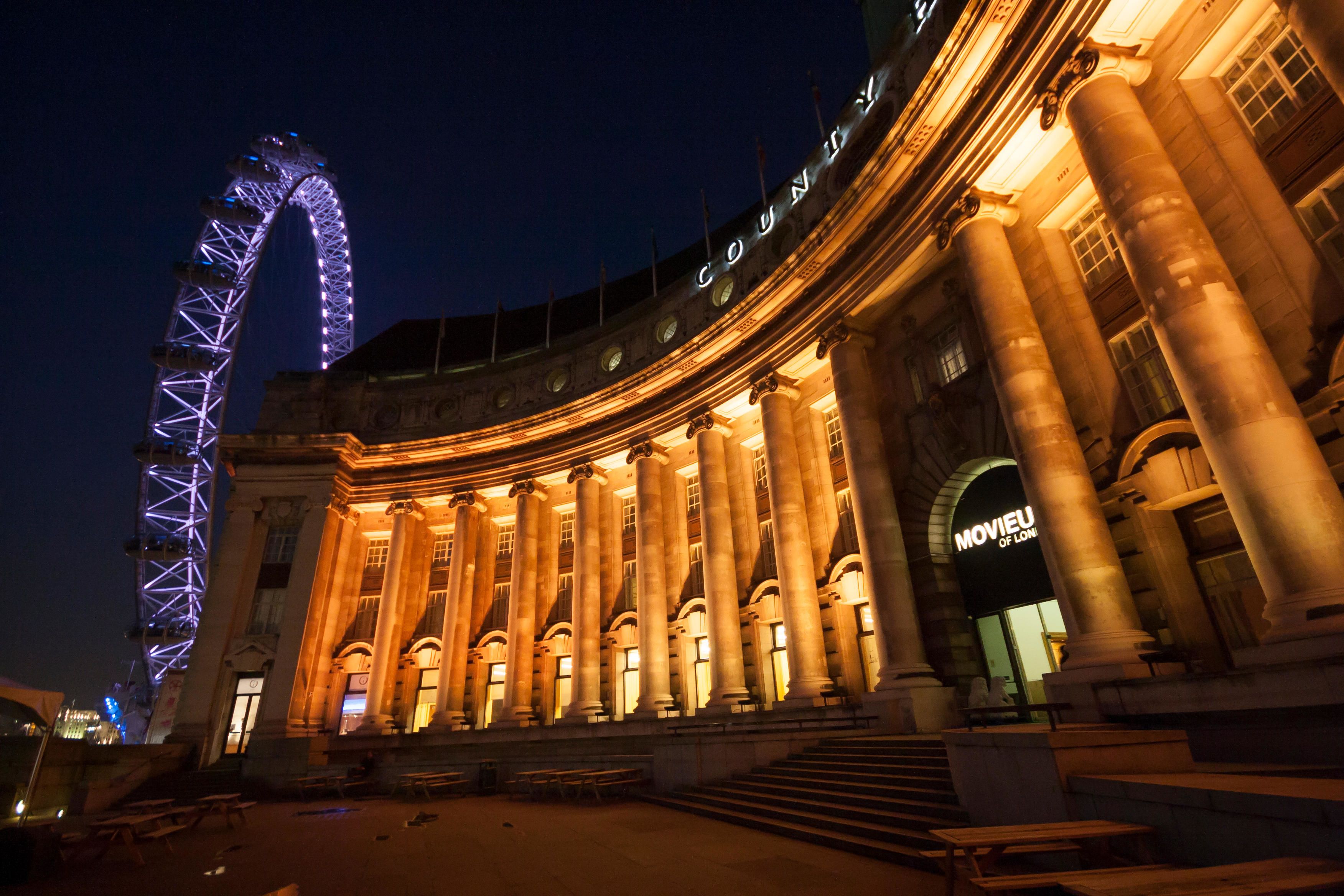 Picture of County Hall by night, with London Eye lit up in background